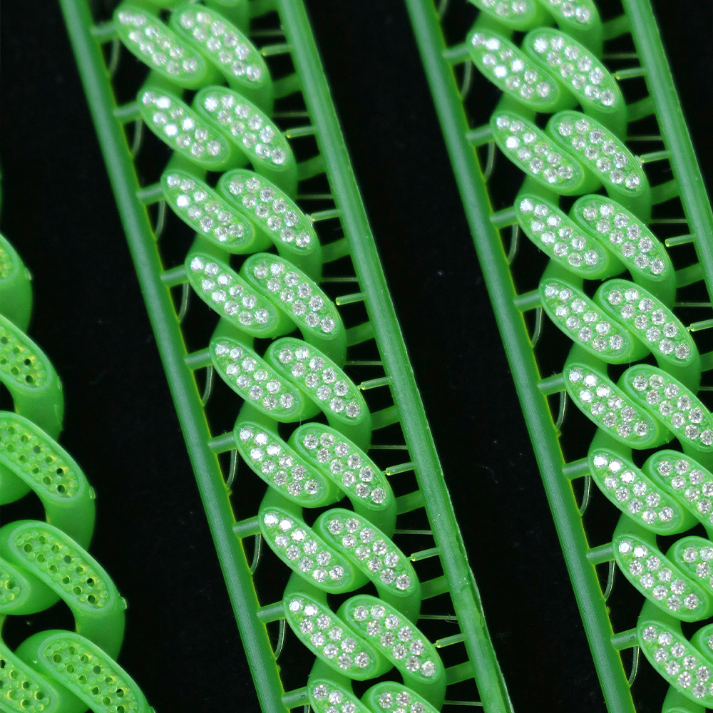 Close - up of bracelets with attached support structures, 3D - printed by iFUN3d using green wax castable resin, embedded with numerous small, shiny crystals