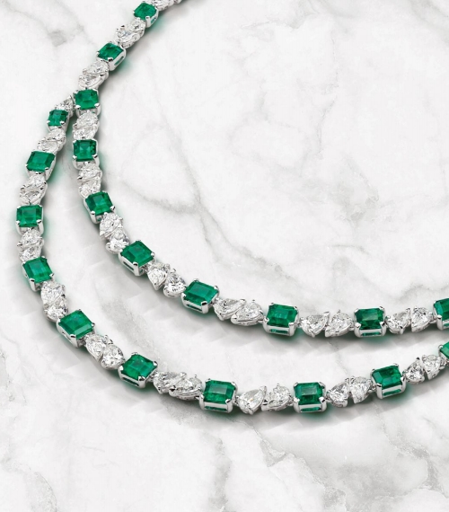 A necklace with a sequence of rectangular - cut, vivid green emeralds evenly placed, interspersed by sparkling pear - shaped and round diamonds, creating a continuous, elegant chain that lies gracefully.