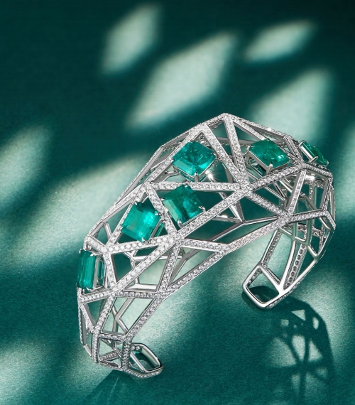 A modern - styled bracelet with a geometric, angular framework. It has large rectangular emeralds set within the framework, and the entire structure is lined with small, twinkling diamonds, giving it a bold and luxurious look.