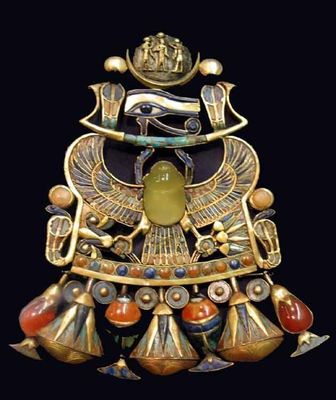 A richly detailed ancient Egyptian jewelry amulet centered around the scarab Khepri. The piece features a large green scarab beetle, golden wings spreading wide, the iconic Eye of Horus above, and clusters of colorful gemstones—including red, blue, and brown stones—paired with ornate pendants, all set against a dark background.