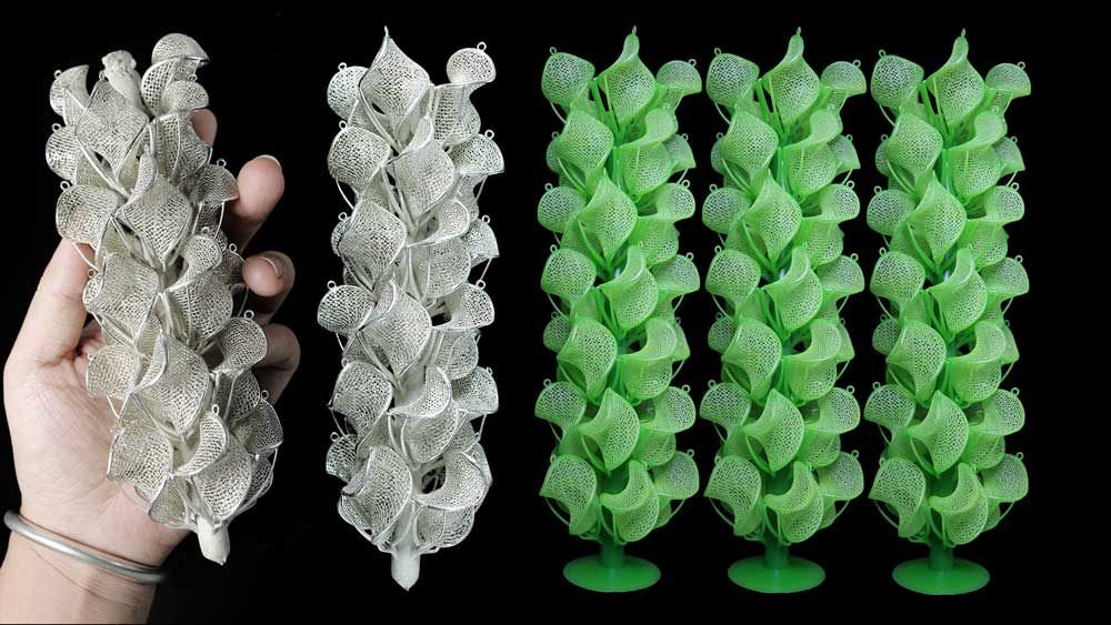 Hand holding white 3D printed earring models alongside green resin earring tree structures prepared for silver casting