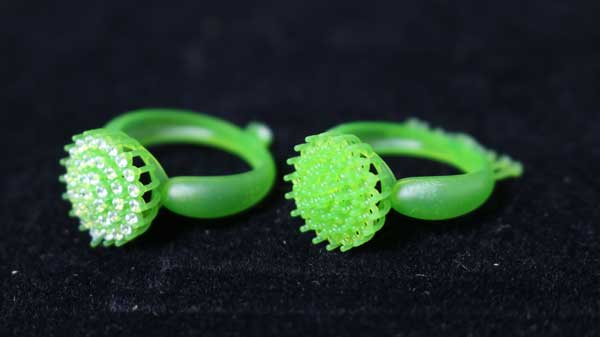 Two 3D - printed green resin rings with circular, diamond - embedded heads and smooth bands