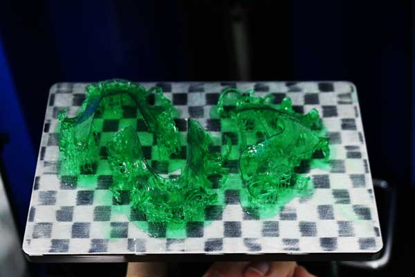 Three complex RPD frameworks freshly printed in green dental casting resin on a 4K 3D printer's build plate, demonstrating the resin's low viscosity and easy printing capabilities for intricate models.
