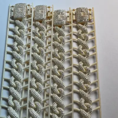 Four 3D printed Cuban link chain models with pave-set stones on complex curves and integral clasp.