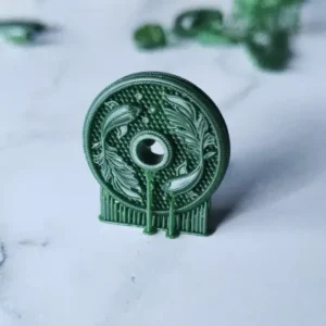 Close-up of a green 3D printed circular jewelry pendant featuring detailed fish and leaf patterns, printed with IFUN 300H high wax castable resin.