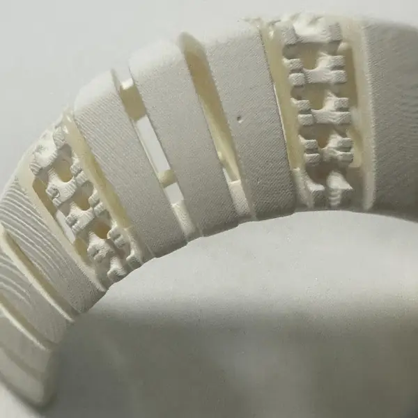 Microscope view of a 3D printed jewelry segment made with white castable resin, showing prominent layer lines and the staircase effect before slicing optimization.