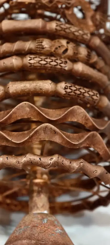 A photograph of a metal jewelry casting tree featuring various bangle designs. The wavy horizontal bangles show surface cracks and cold shut defects caused by high-wax resin burnout issues.