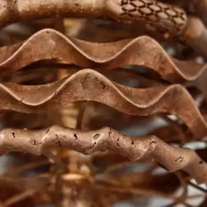 A photograph of a metal jewelry casting tree featuring various bangle designs. The wavy horizontal bangles show surface cracks and cold shut defects caused by high-wax resin burnout issues.