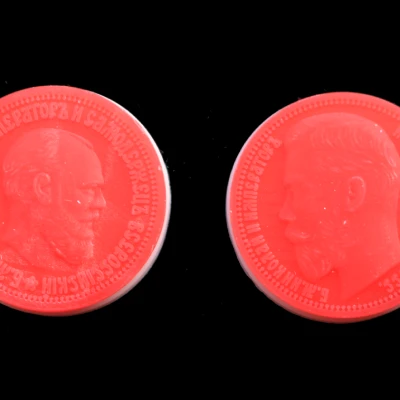 Realistic portrait relief medallions 3D printed in red casting wax.