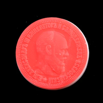 Top view of a red 3D printed wax coin model replicated from a historical Russian Alexander III commemorative medal, featuring sharp embossed cyrillic text and a detailed portrait relief.