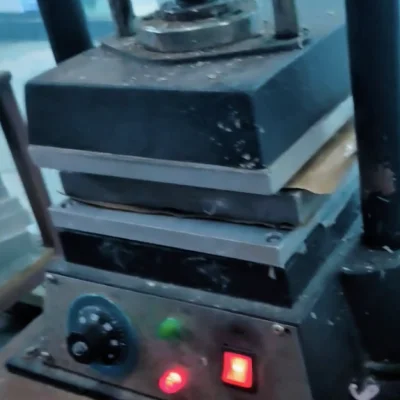 An industrial desktop jewelry rubber mold vulcanizer machine with dual heated metal plates clamping down tightly on a mold frame under high temperature and mechanical pressure.