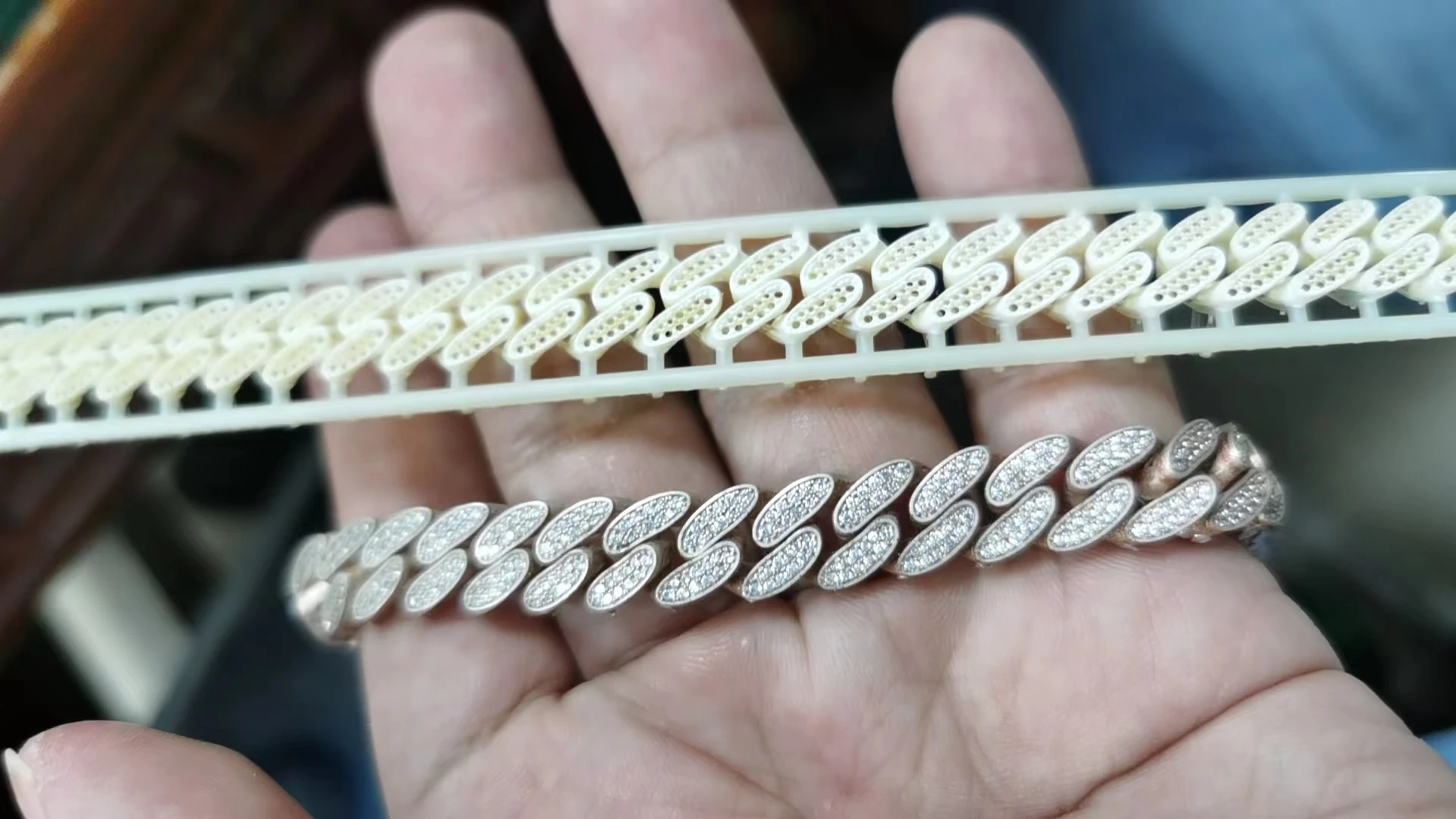 Hand holding 3D printed resin Cuban bracelet pattern next to finished silver iced-out Cuban bracelet with pre-set stones
