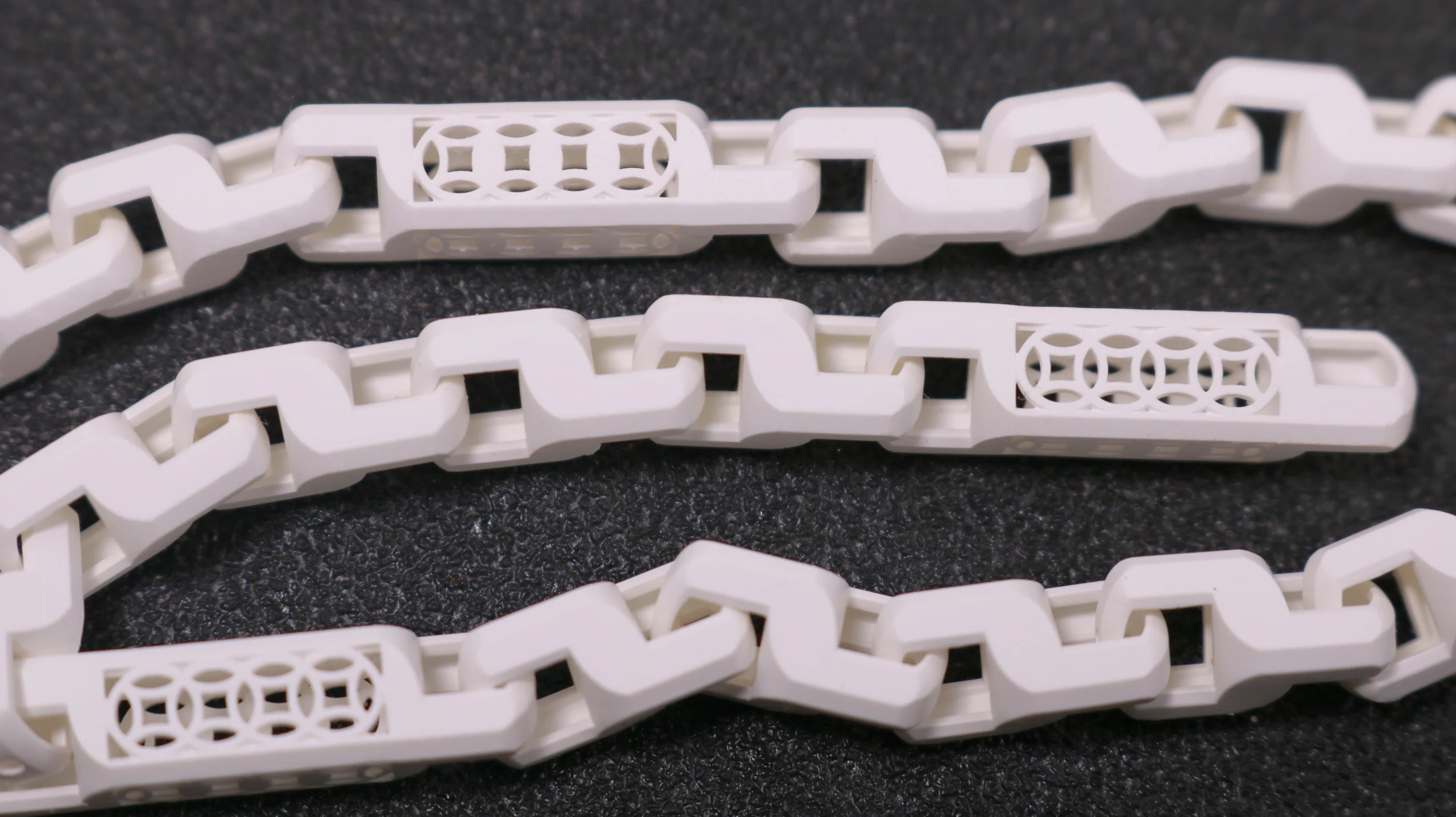 Close-up view of 3D printed flexible articulated link bracelet in 800D white wax resin with supports removed