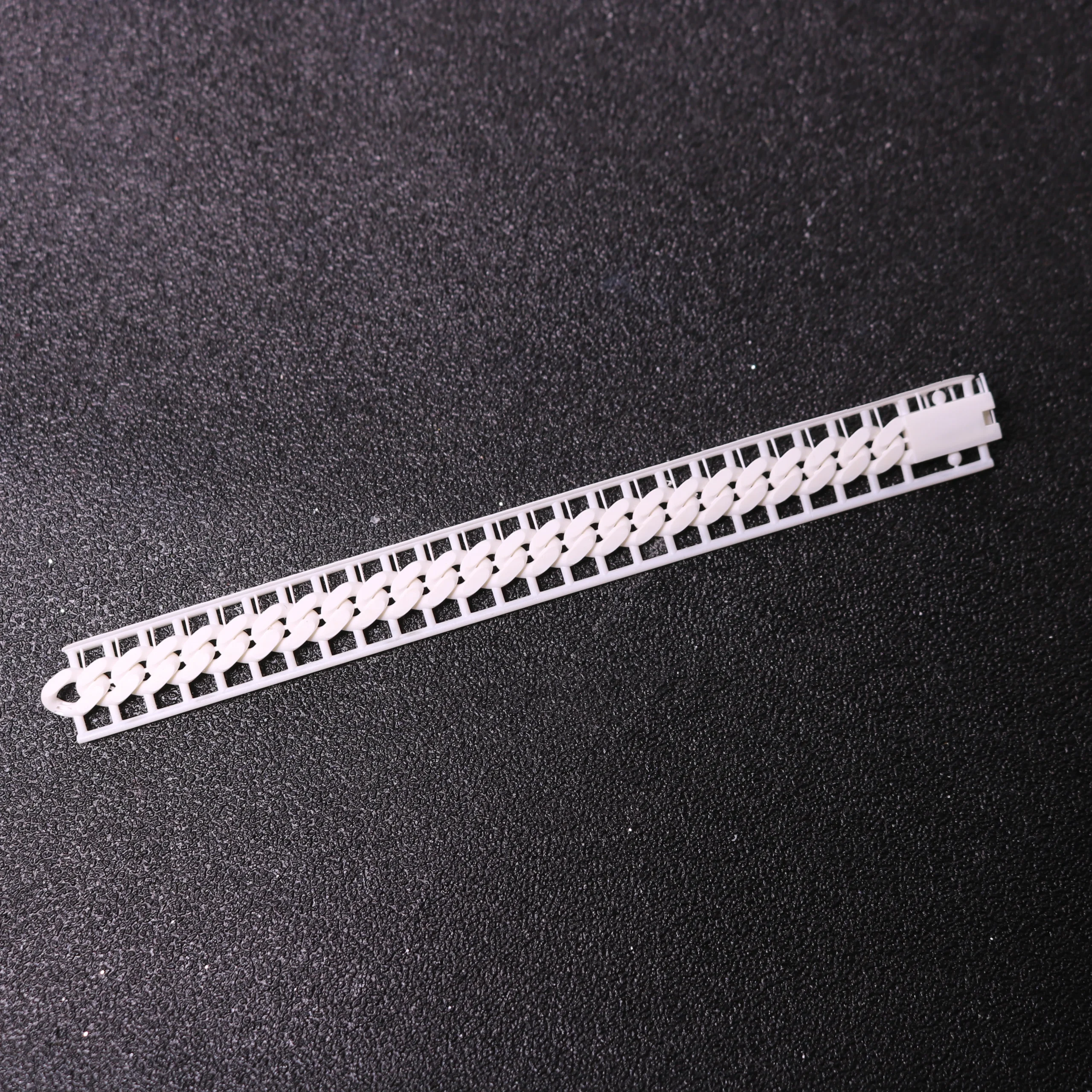 Top view flat lay of 3D printed plain Cuban link chain pattern with sprues made of 800D white wax resin