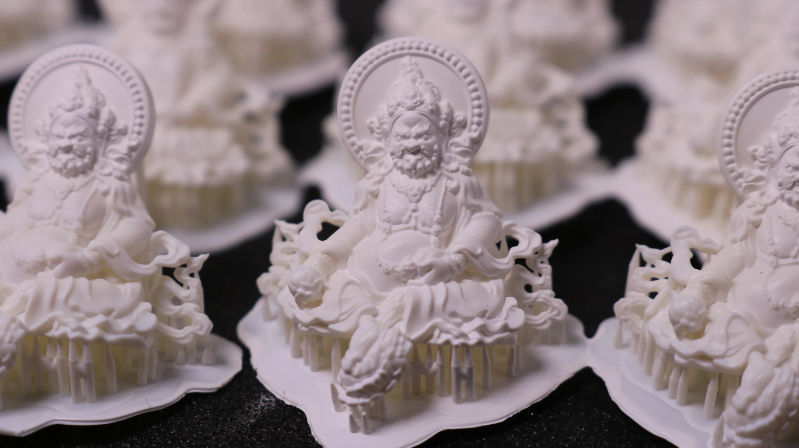 Close-up front view of 3D printed Buddha figure pendants in 800D white wax resin