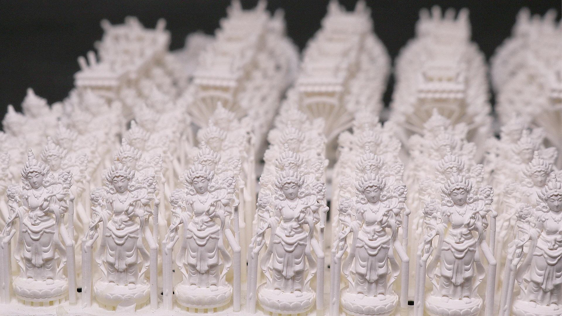 Perspective view of mass batch 3D printed Buddha figure pendants in 800D white wax resin
