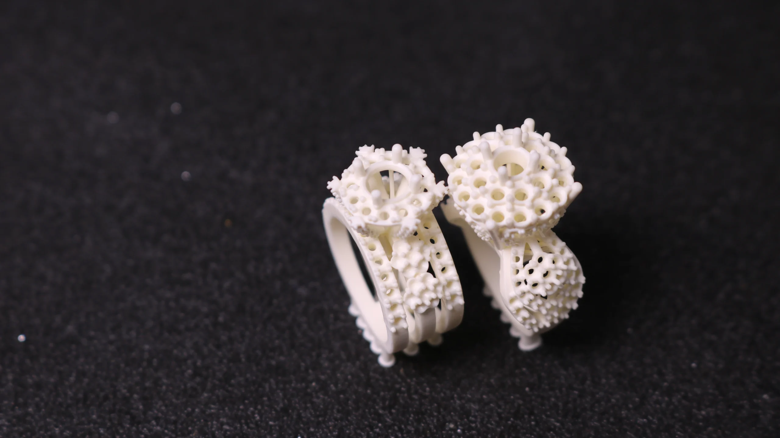 Perspective view of two 3D printed cluster pave ring patterns with dense setting holes in 800D white wax resin