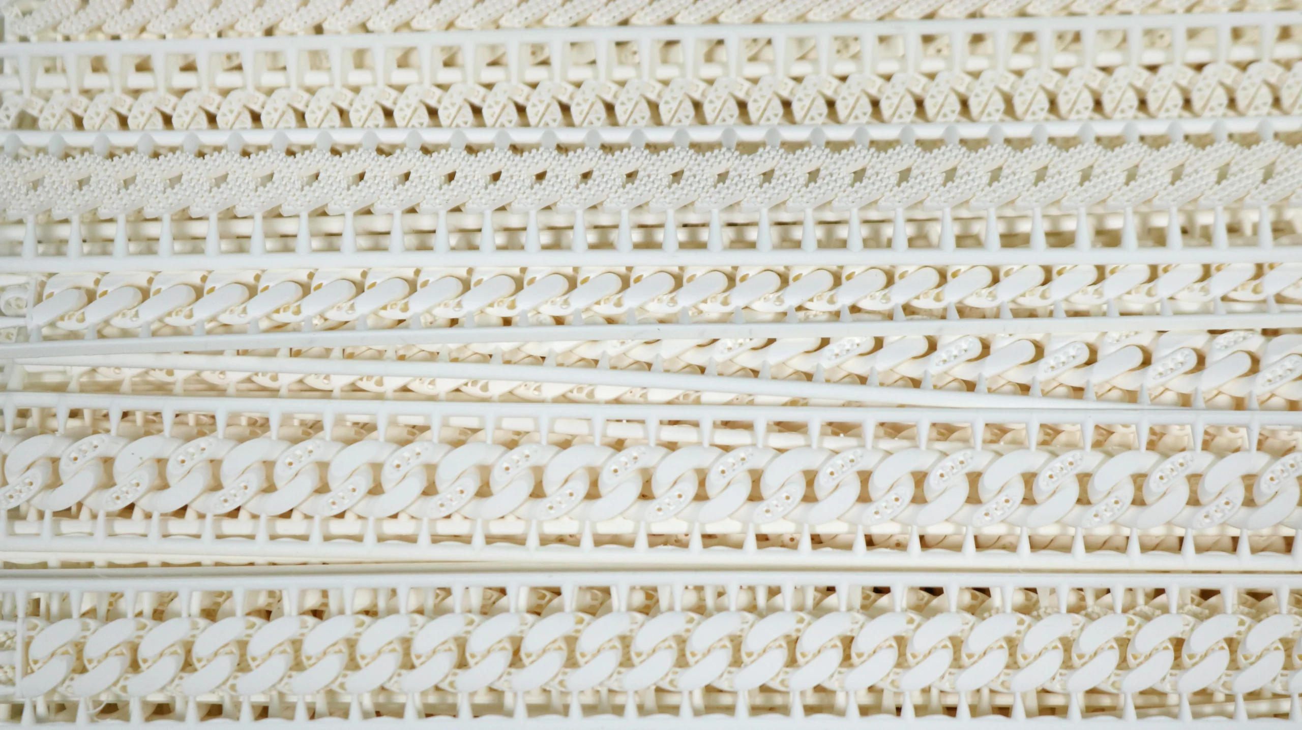 Top view of stacked 3D printed 800D white wax resin Cuban link bracelets with stone setting holes
