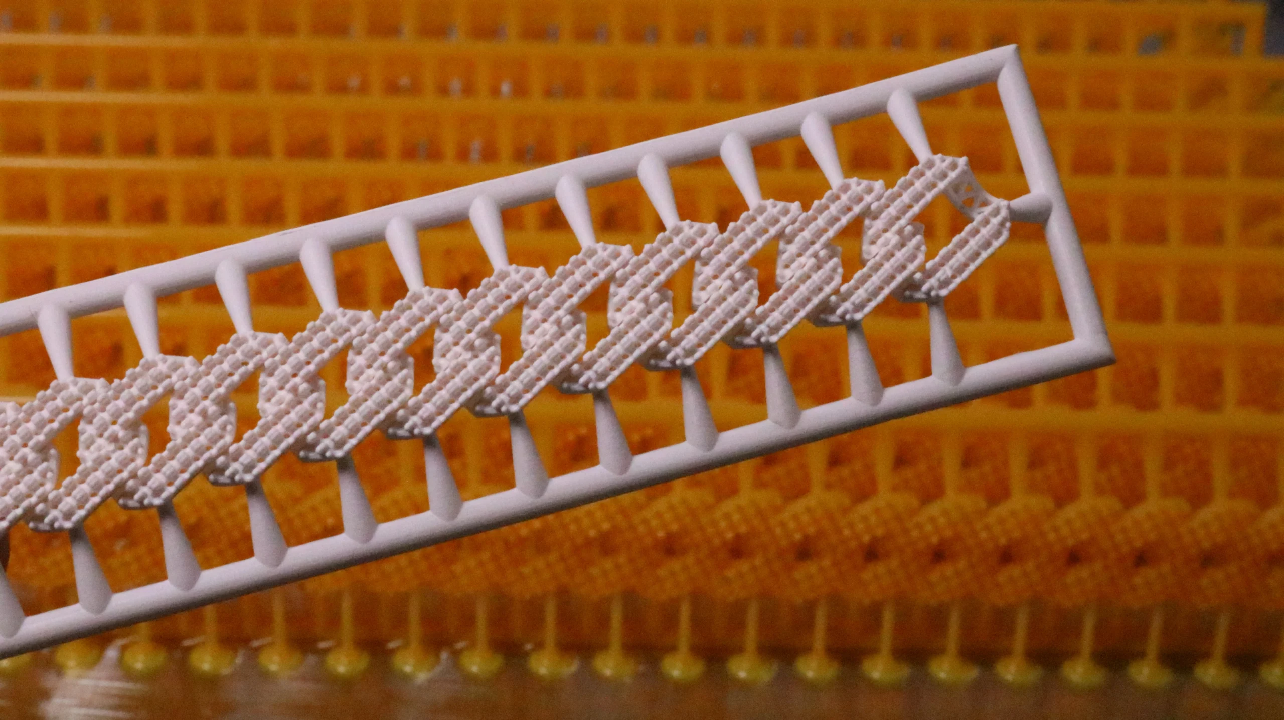 Close-up view of cured 800D white wax resin Cuban link chain pattern against batch printed uncured background