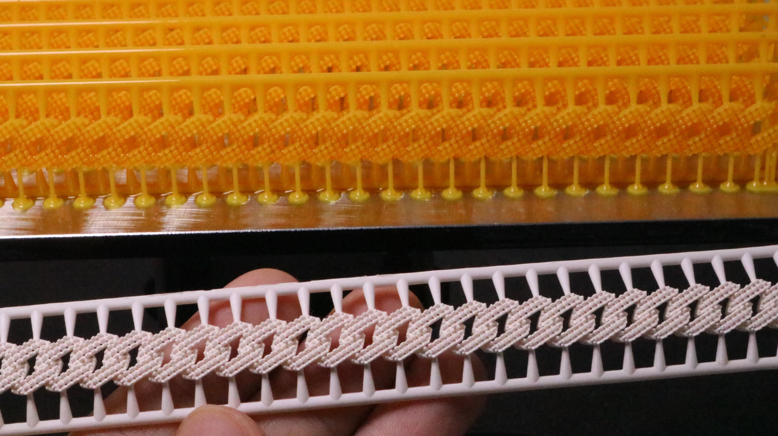 Single cured 800D white wax resin Cuban link pattern held in front of batch uncured print plate