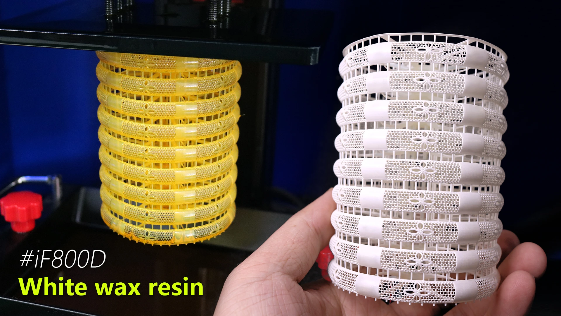 Hand holding cured 800D white wax resin filigree bangles stack next to uncured batch on build plate