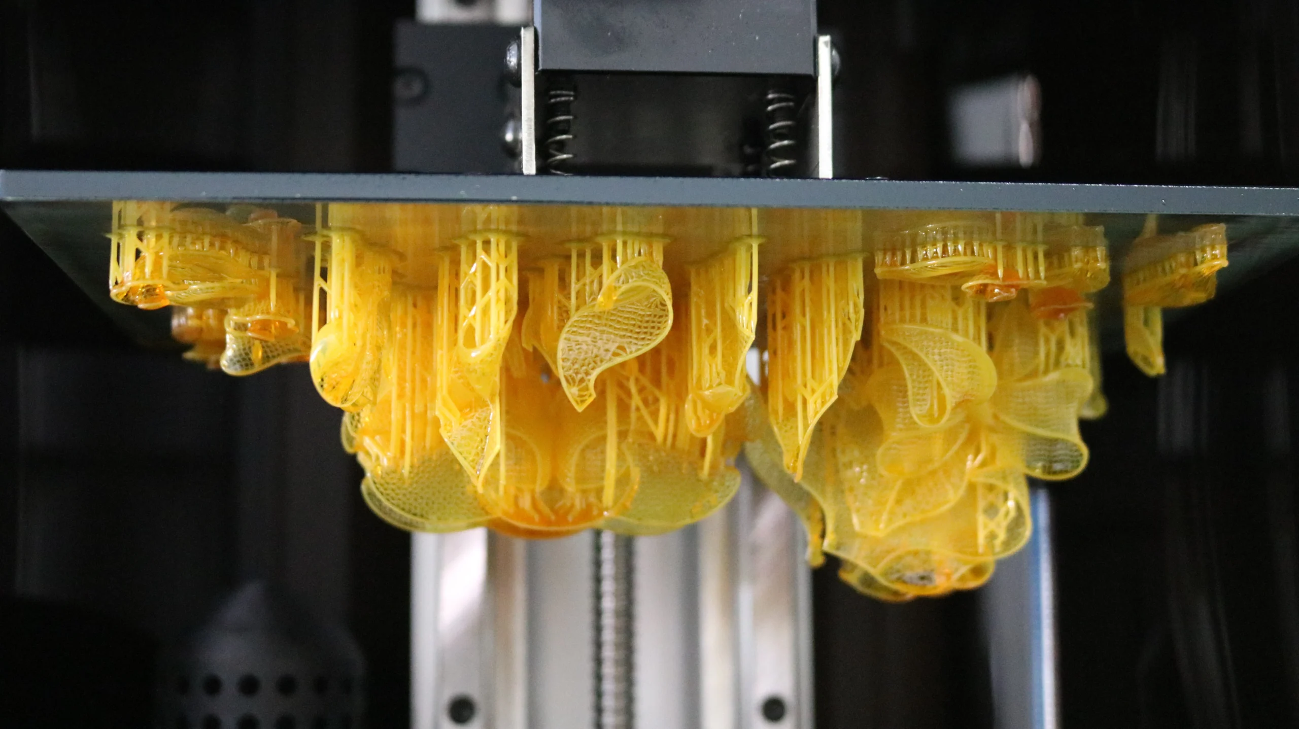 Freshly 3D printed 800D white wax resin filigree floral necklace components on build plate before removal
