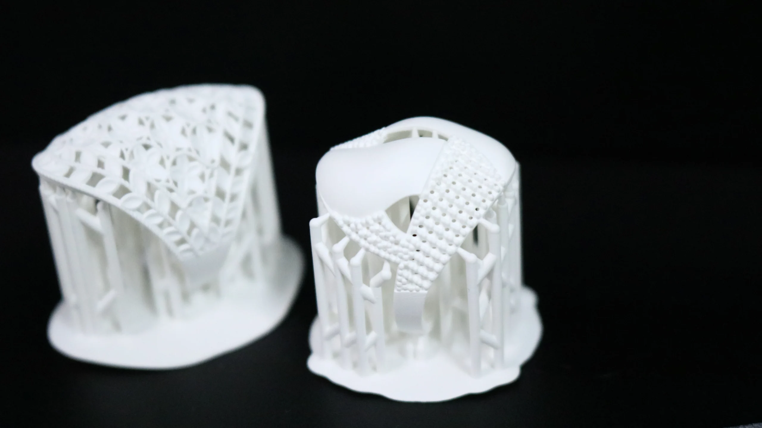 Front view of two 3D printed statement rings with supports in 800D white wax resin featuring filigree and stone setting holes