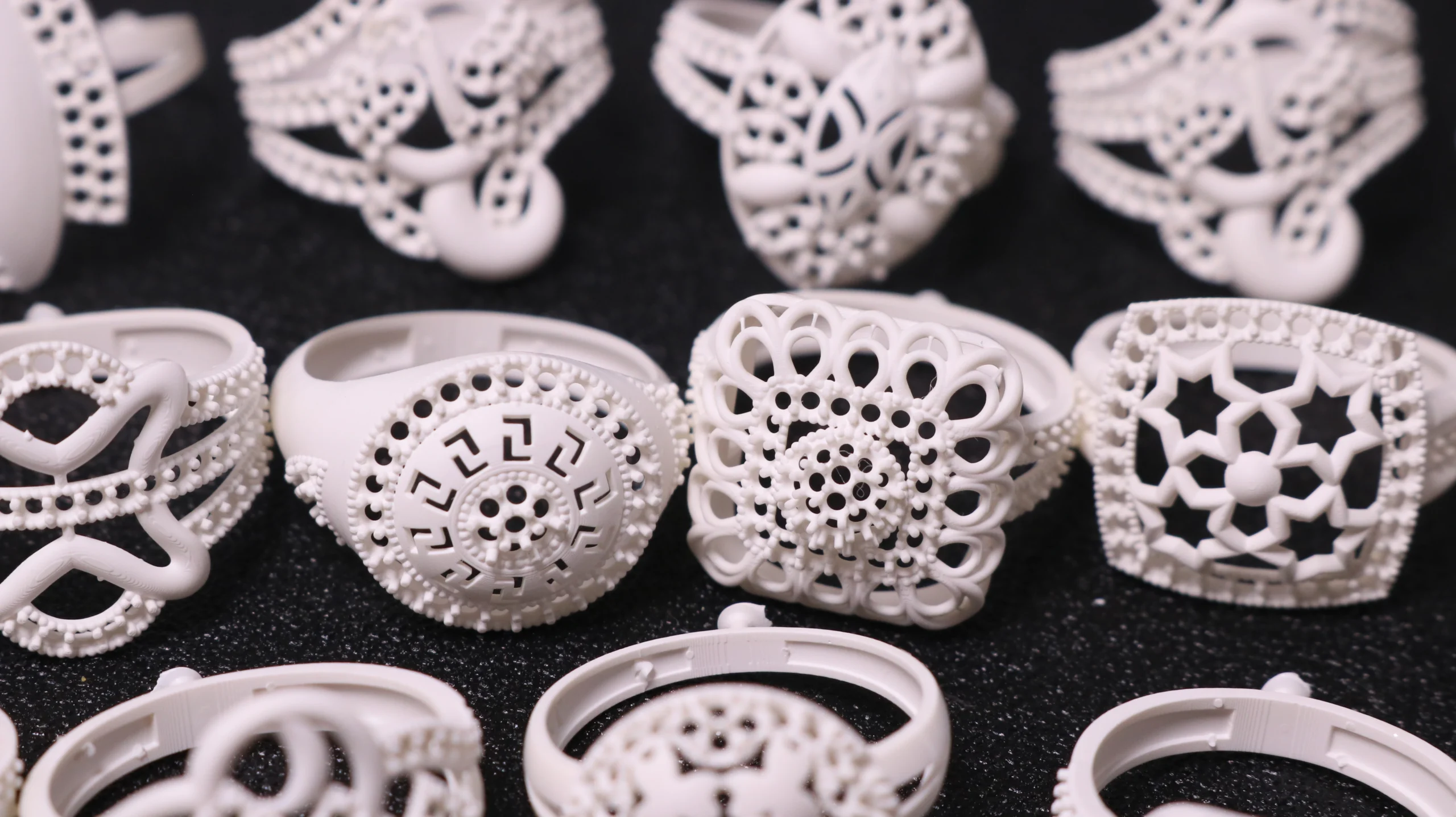 Close-up view of multiple 3D printed intricate carved and filigree rings made with 800D white wax resin