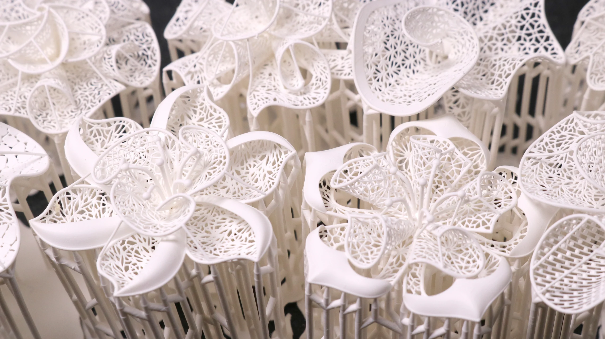 Macro close-up view of 3D printed intricate floral blossom filigree rings on supports in 800D white wax resin