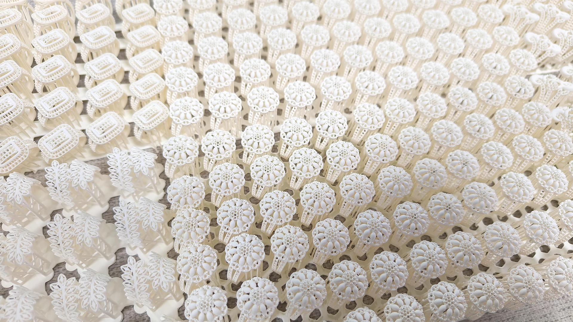 Perspective top view of full plate batch 3D printed floral pave rings in 800D white wax resin