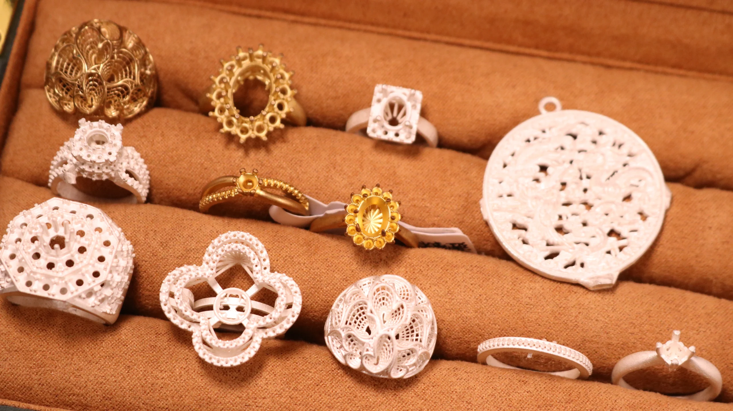 Top view of jewelry display tray featuring 3D printed resin patterns and finished gold cast rings and pendants