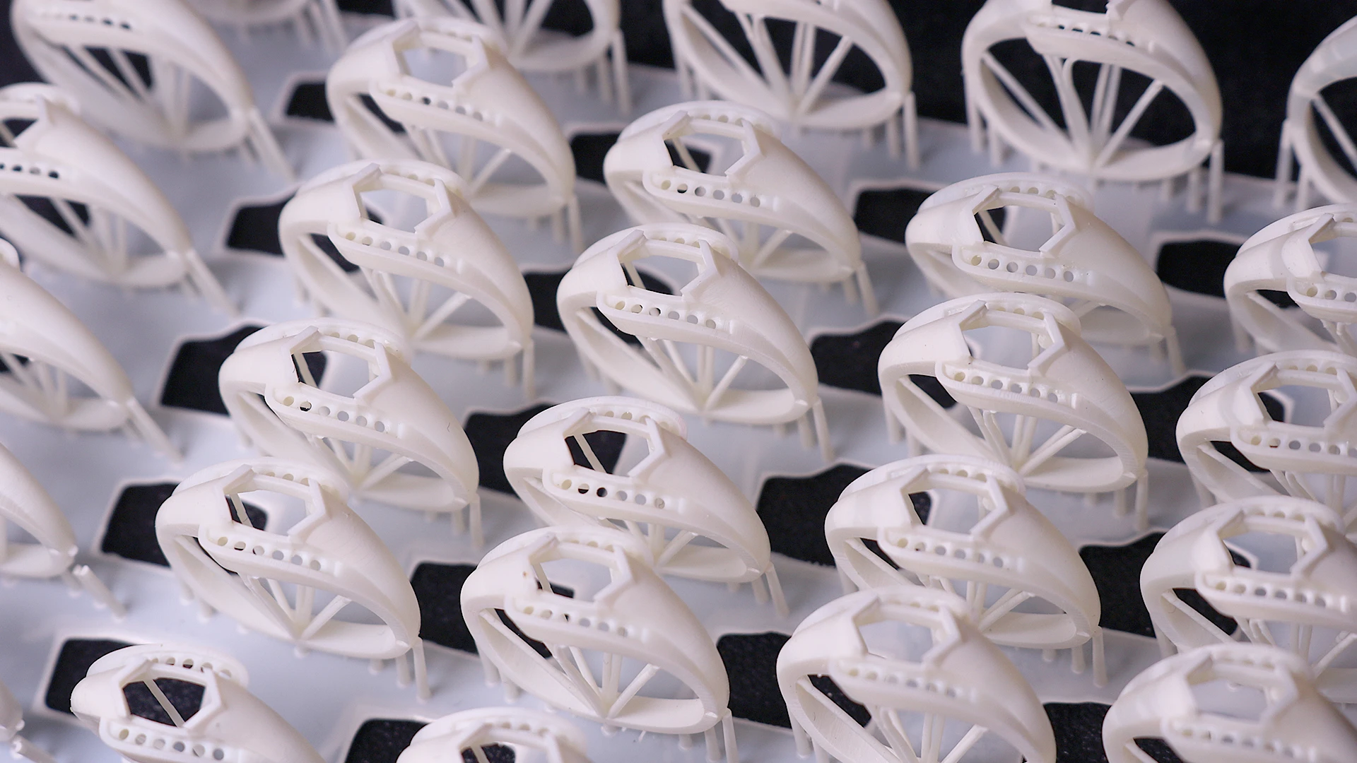 Perspective top view of batch 3D printed hexagon pave ring mountings in 800D white wax resin