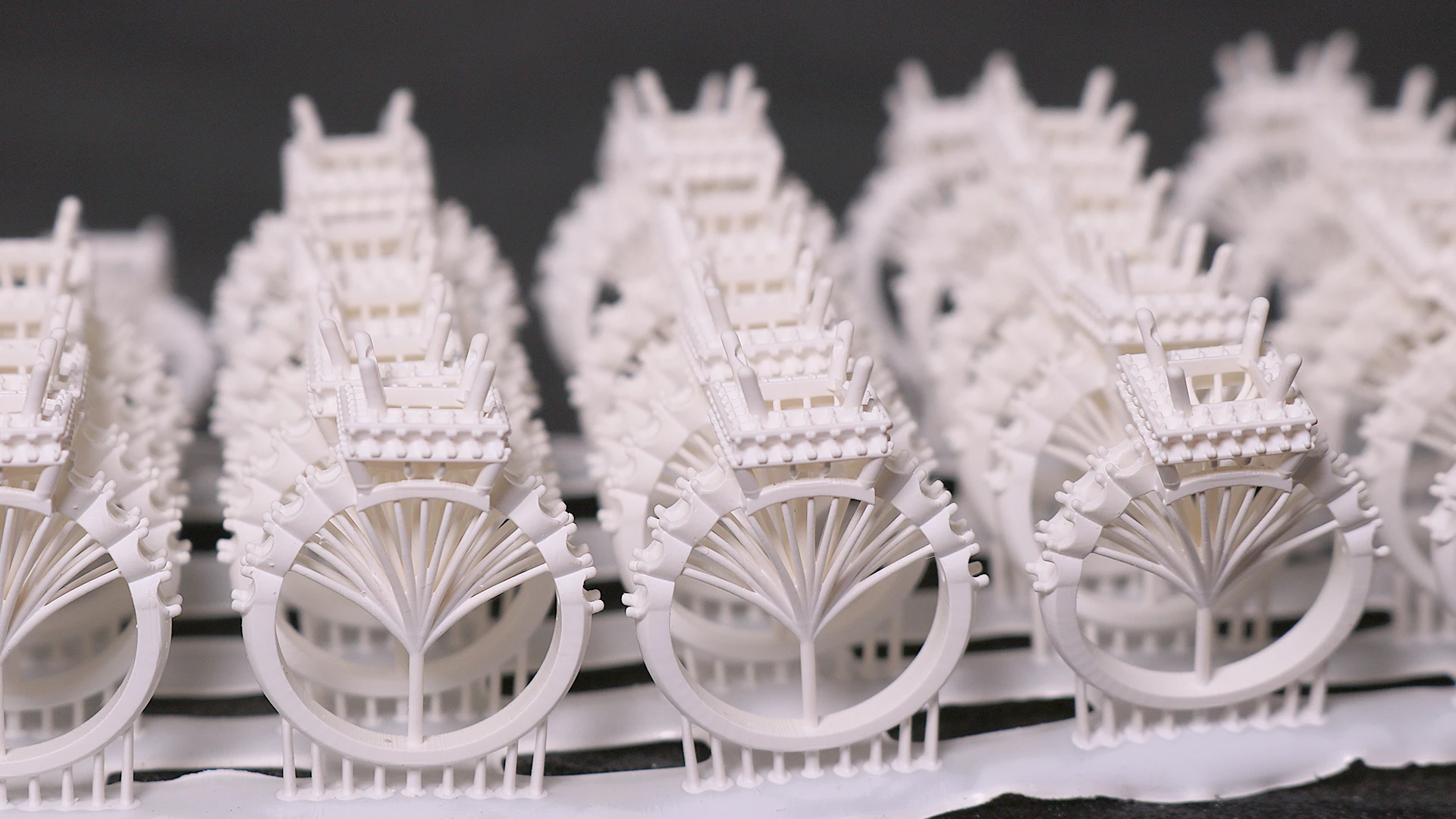 Perspective front view of batch 3D printed solitaire pave ring mountings with main stone prongs in 800D white wax resin