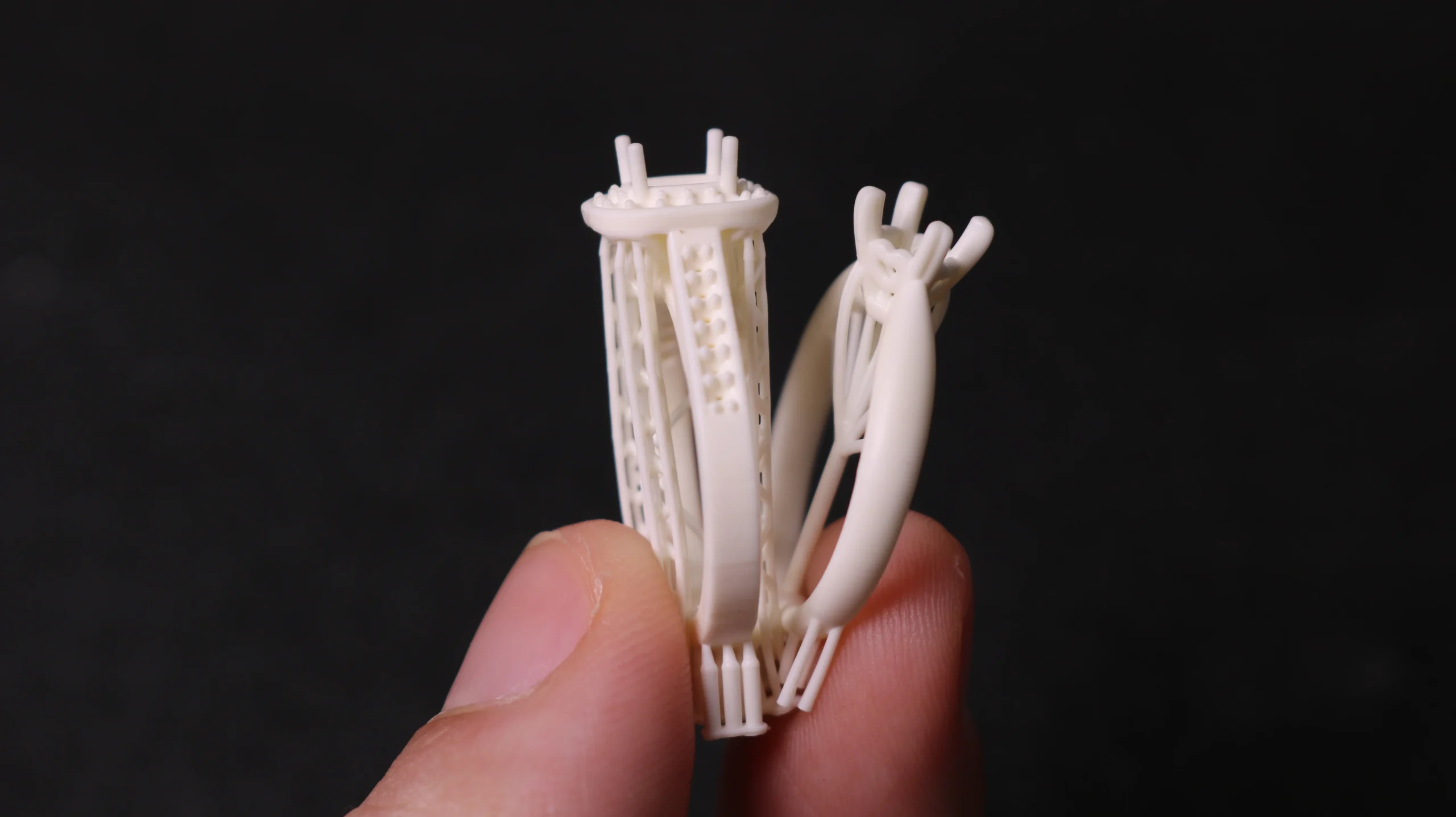 Handheld close-up side view of two 3D printed solitaire pave ring mountings in 800D white wax resin
