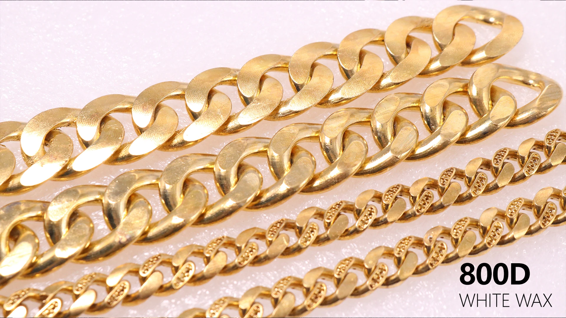 Top view flat lay of four gold cast Cuban link chains featuring plain polished and stone-setting hole styles