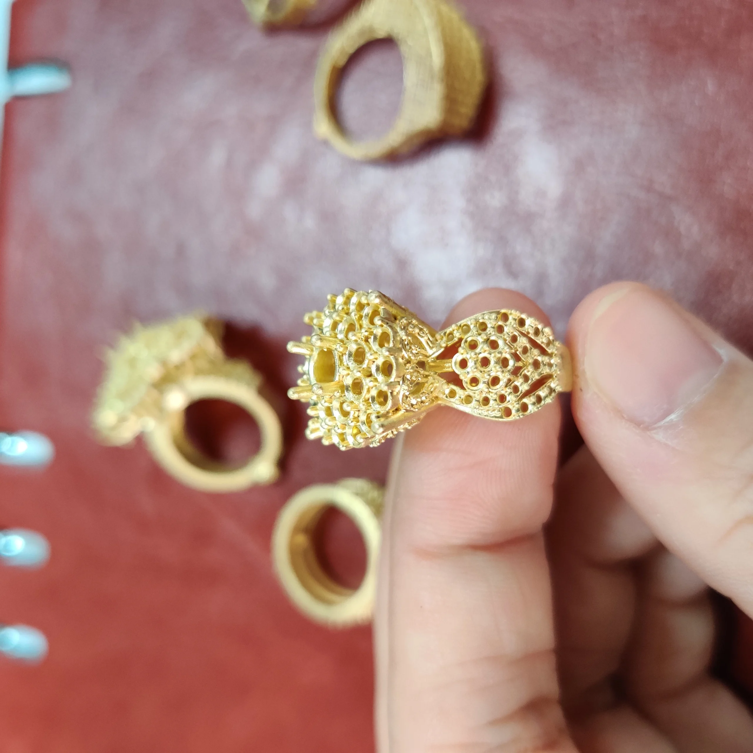 Hand-held close-up side view of gold cast pave statement ring shank showing stone setting holes