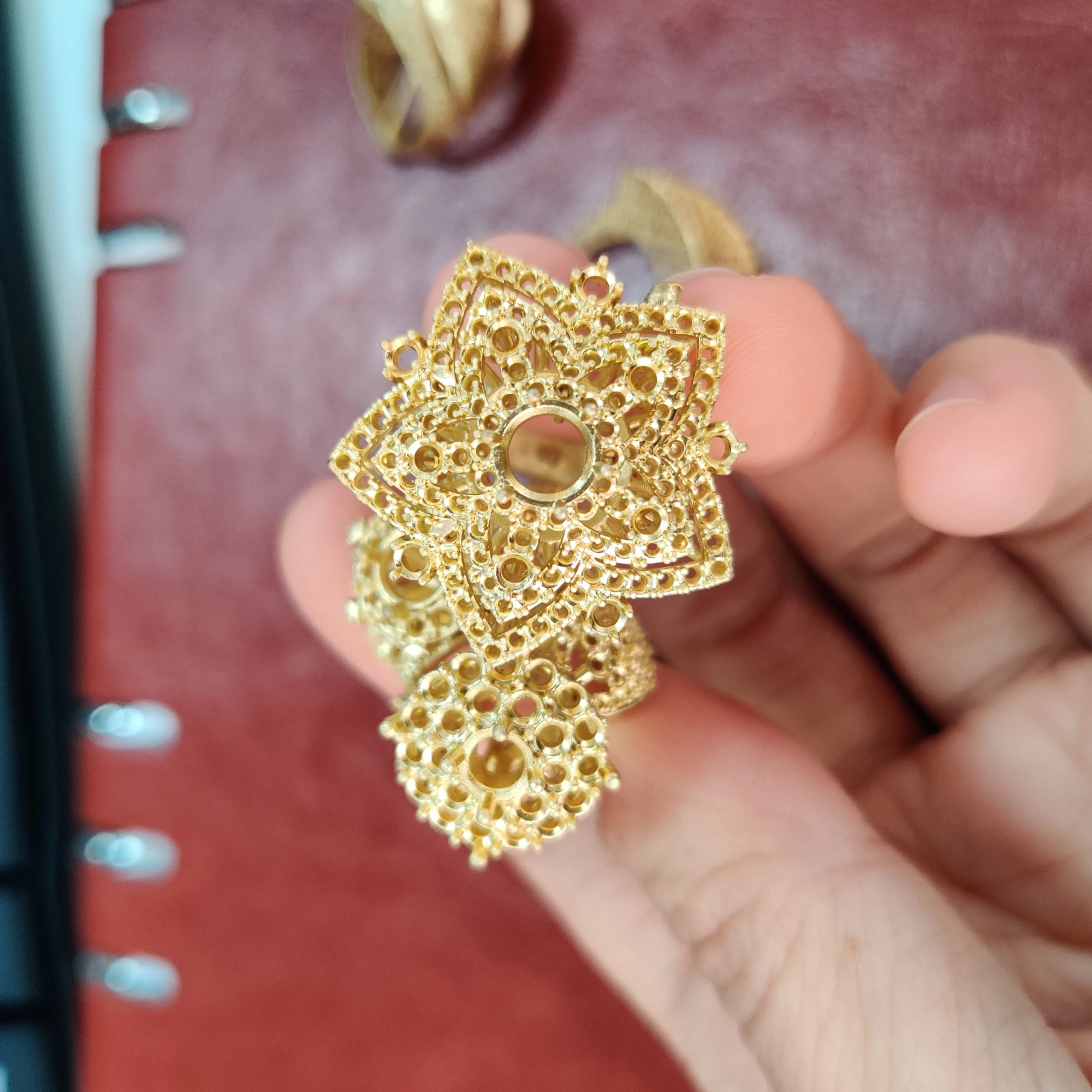 Hand-held top view of gold cast star-shaped and round statement rings with stone setting holes