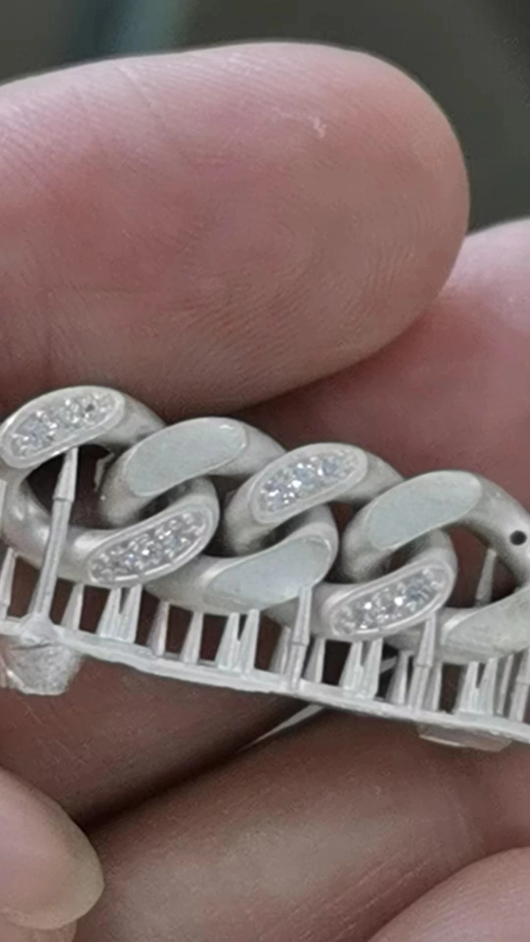 Close-up view of silver cast iced-out Cuban link with sprues and pre-set stones via direct resin casting